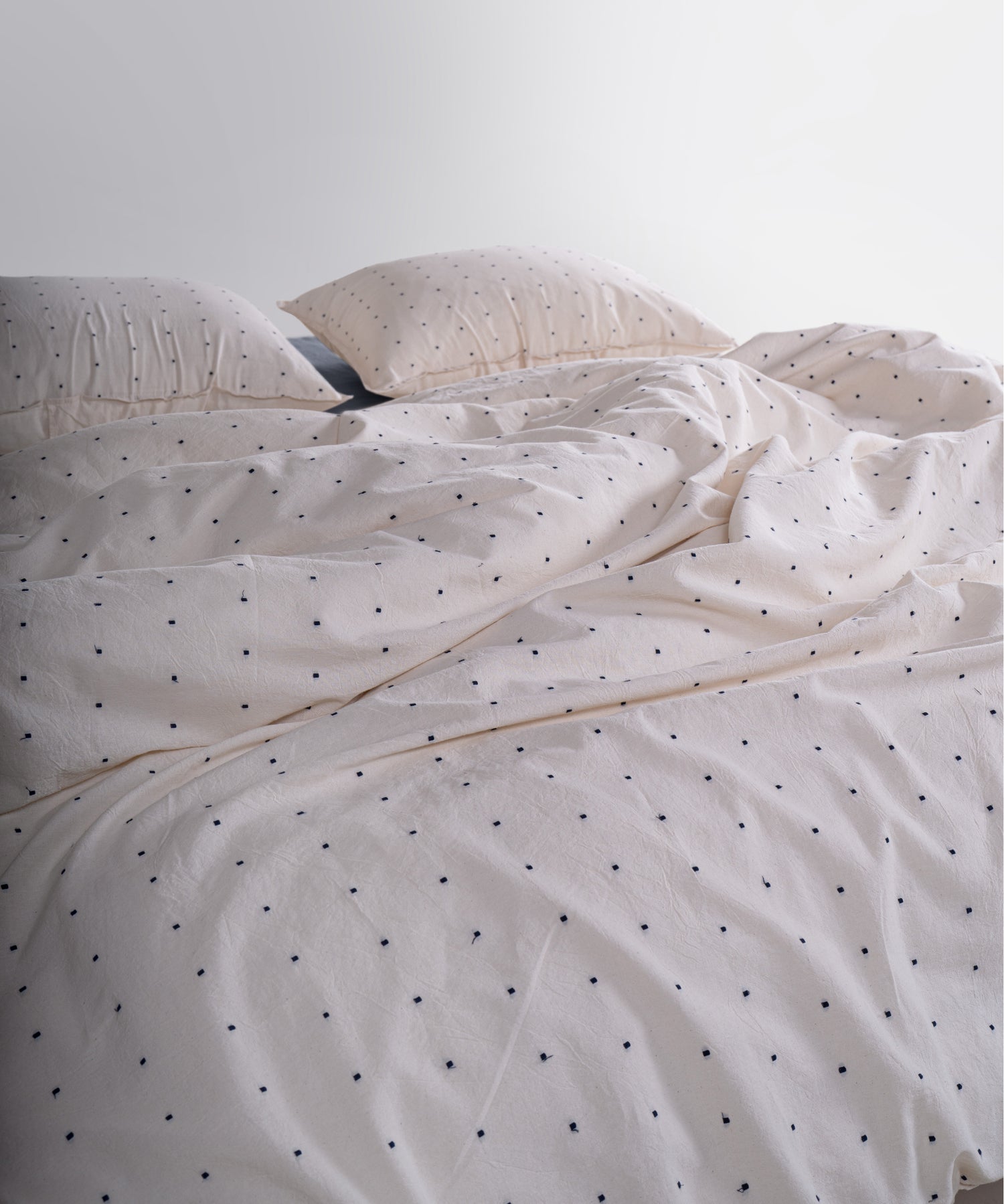 Close-up of garment washed cotton fabric showing natural cream yarn with black speckled texture