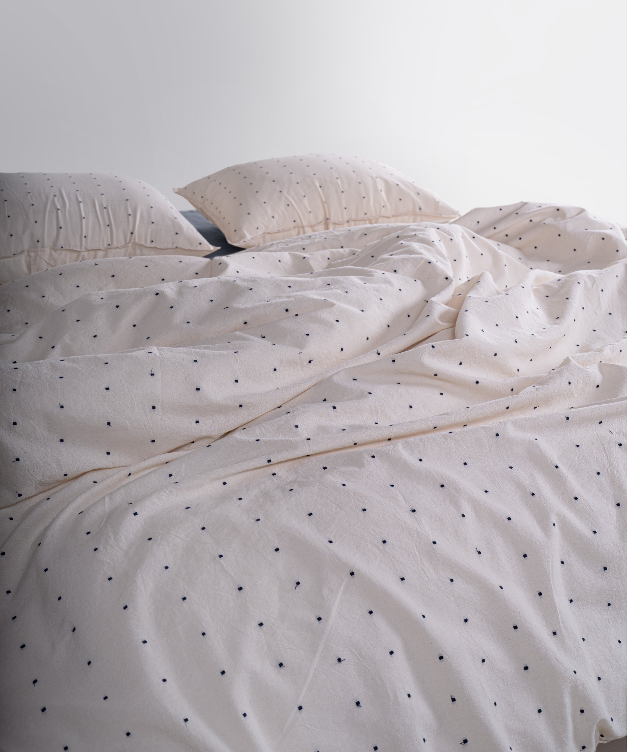 Close-up of garment washed cotton fabric showing natural cream yarn with black speckled texture