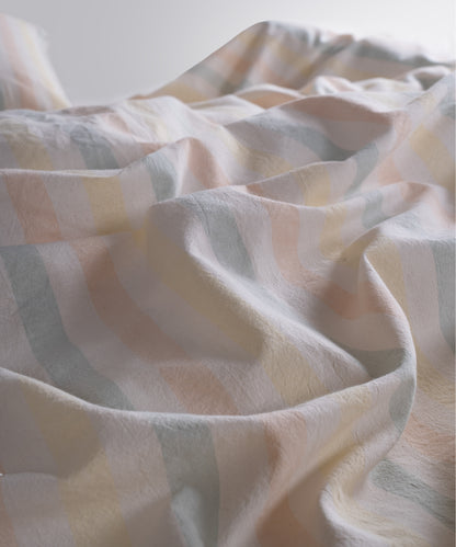Close-up of garment washed cotton fabric showing natural cream base with soft blue, blush and yellow stripes summer

