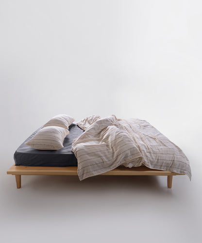 Natural cream and navy striped cotton duvet cover set styled on bed with relaxed modern interior