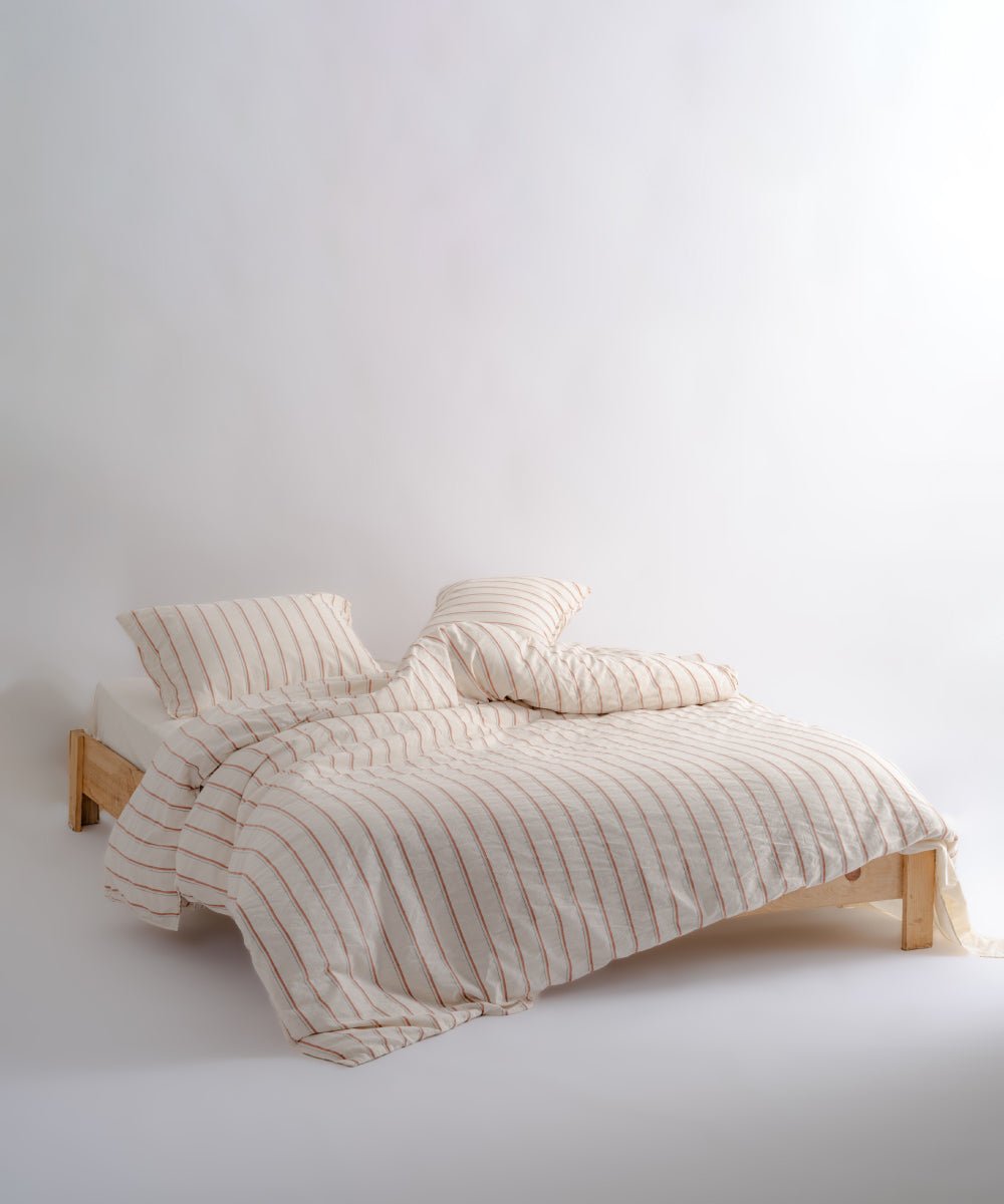 Natural cream cotton duvet cover set with red stripes styled on a double bed