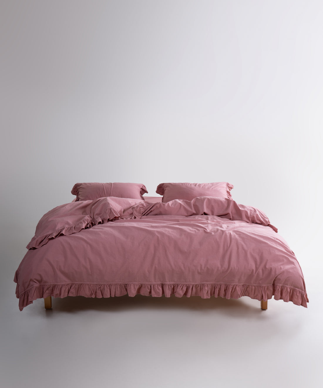 Old rose stonewashed cotton duvet cover set displayed on bed with ruffled edges and soft texture