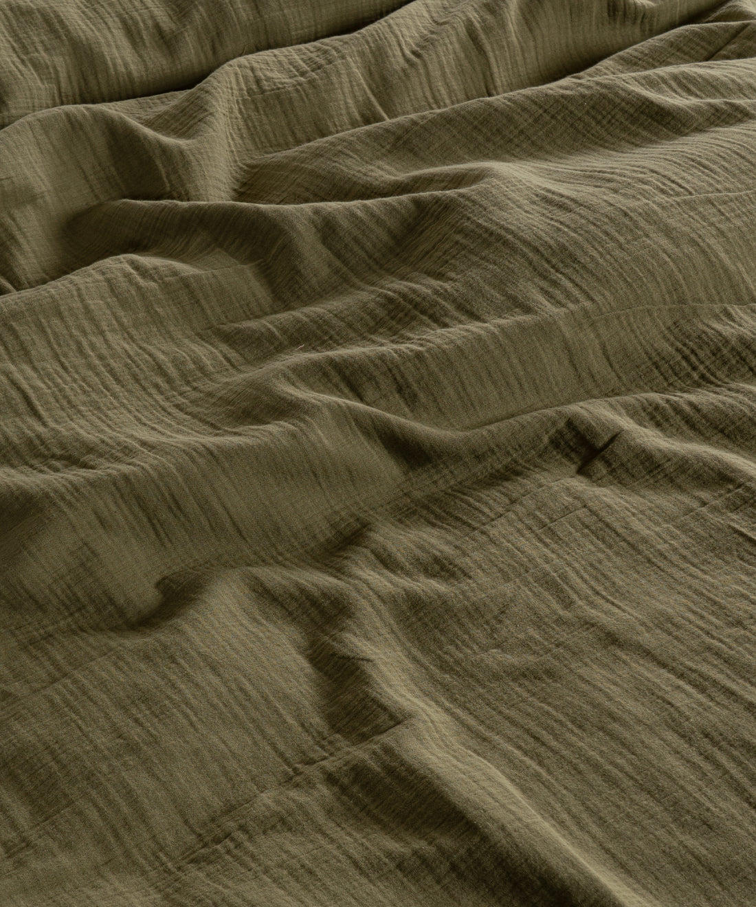 Cloud 100% Cotton Gauze-Muslin Duvet Cover Set Olive casually tousled on a low wooden platform bed – Limasso London
