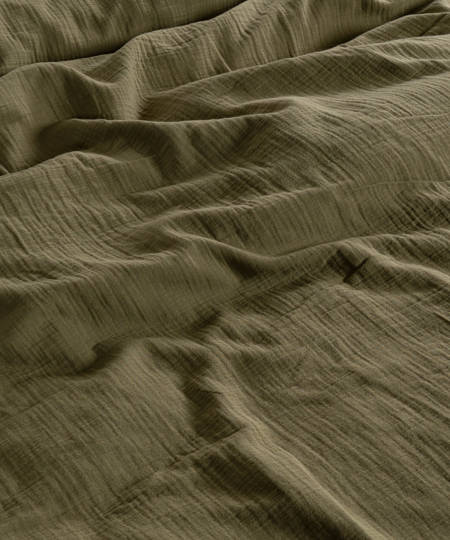 Cloud 100% Cotton Gauze-Muslin Duvet Cover Set Olive casually tousled on a low wooden platform bed – Limasso London