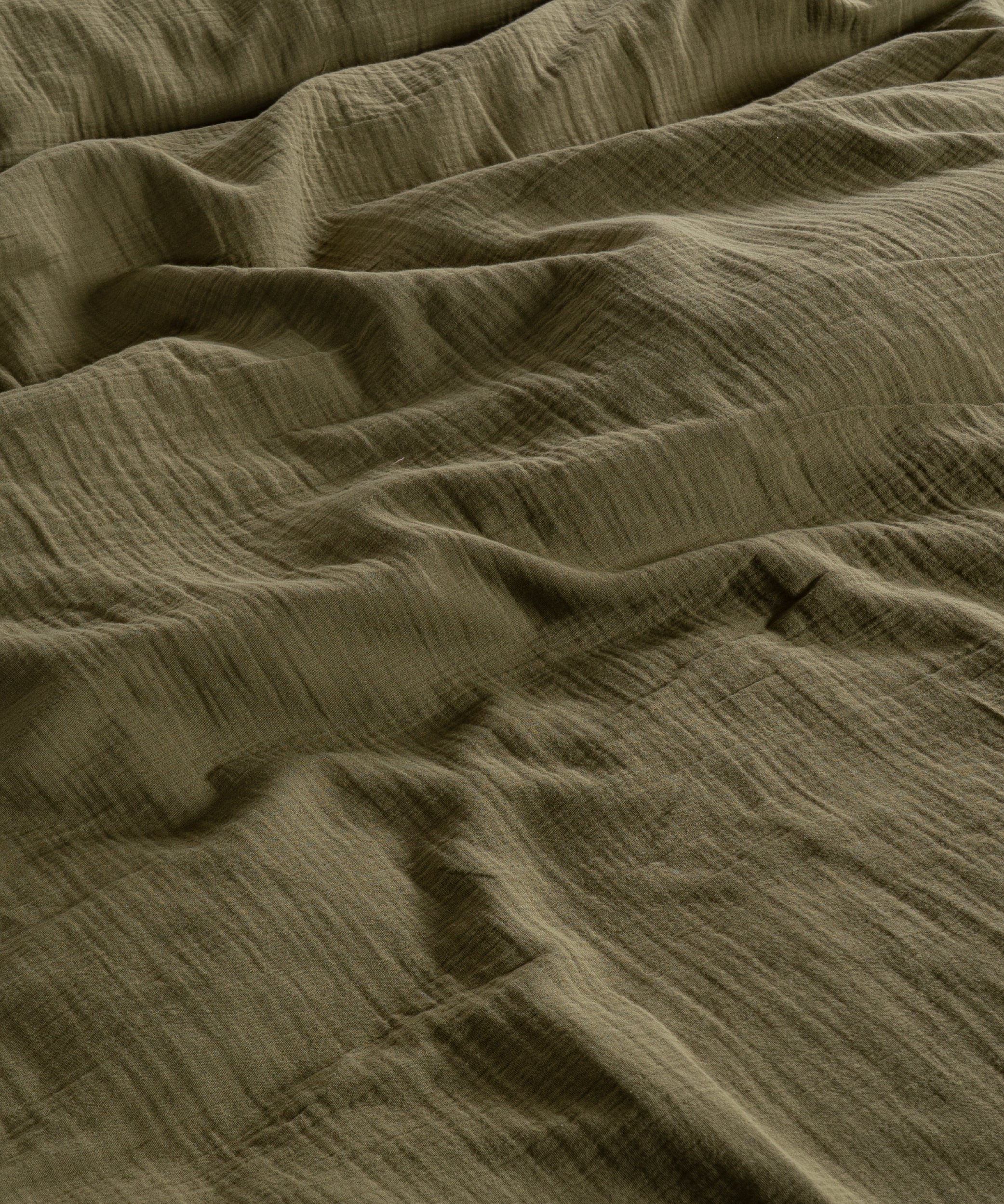 Cloud 100% Cotton Gauze-Muslin Duvet Cover Set Olive casually tousled on a low wooden platform bed – Limasso London