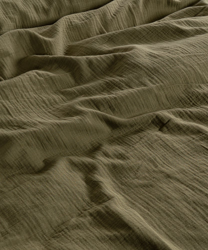 Cloud 100% Cotton Gauze-Muslin Duvet Cover Set Olive casually tousled on a low wooden platform bed – Limasso London