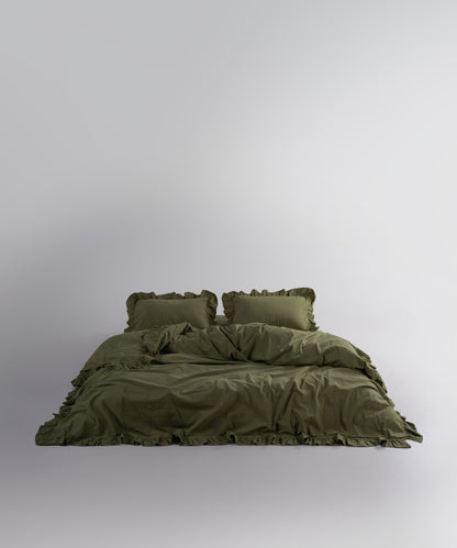 Capulet Olive stonewashed cotton duvet cover set displayed on bed with soft ruffle edges
