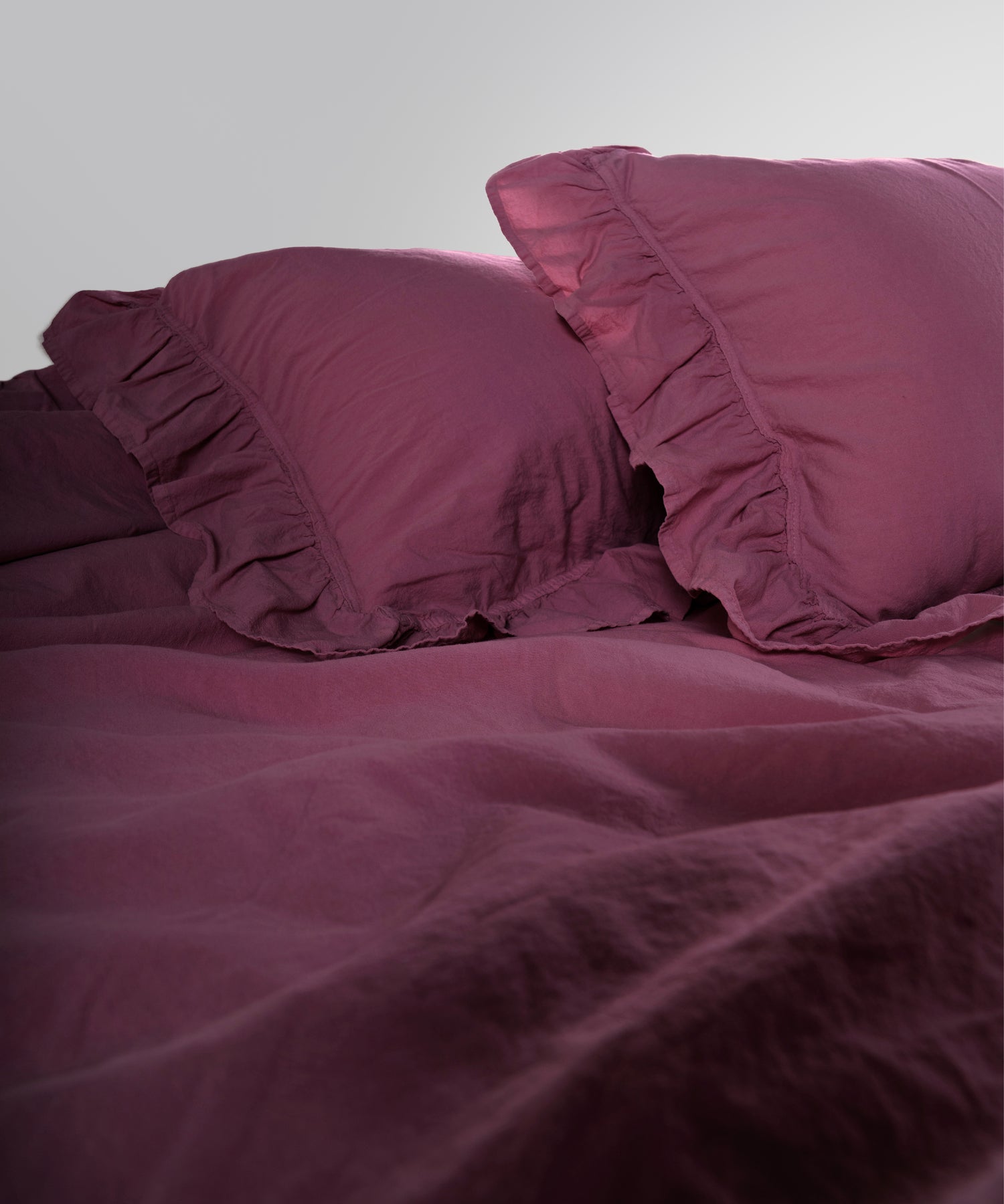 Close-up of stonewashed 100% cotton duvet cover fabric in raspberry colour showing soft texture
