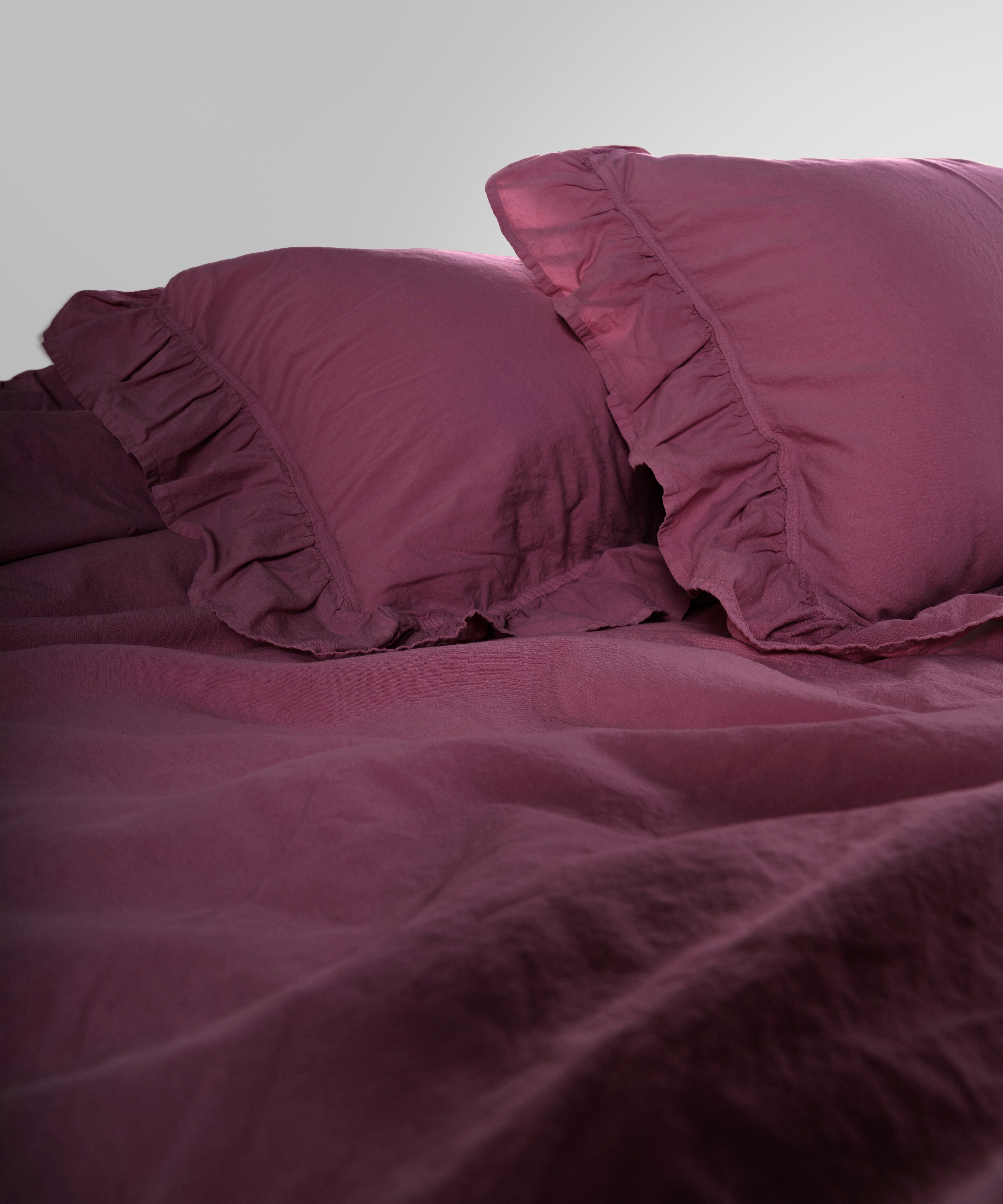 Close-up of stonewashed 100% cotton duvet cover fabric in raspberry colour showing soft texture